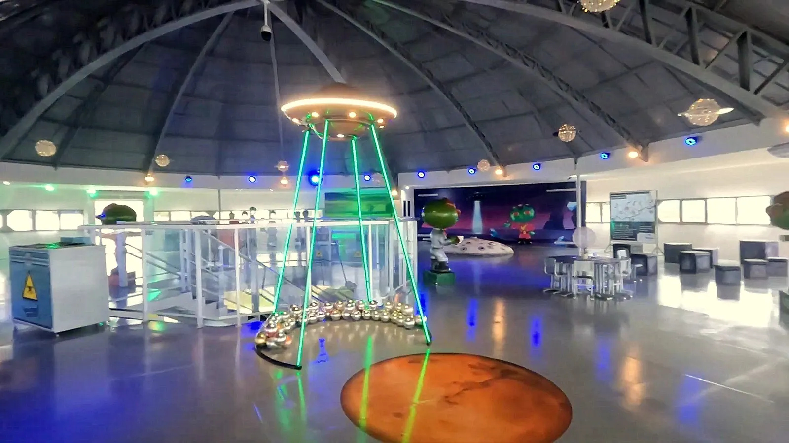 Interior do Memorial do ET de Varginha, com réplica de disco voador suspensa e cenário temático